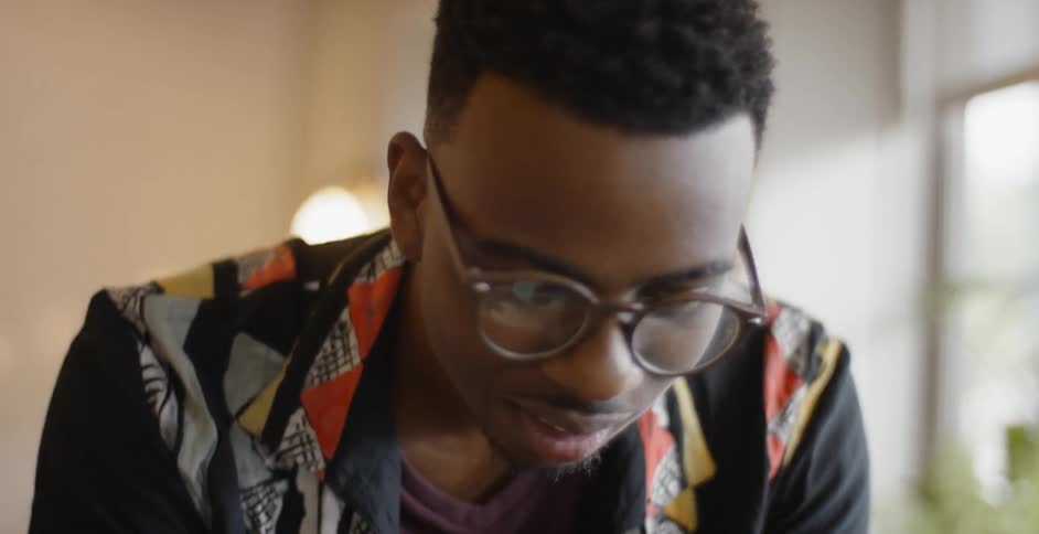 A young black man is talking and bending over