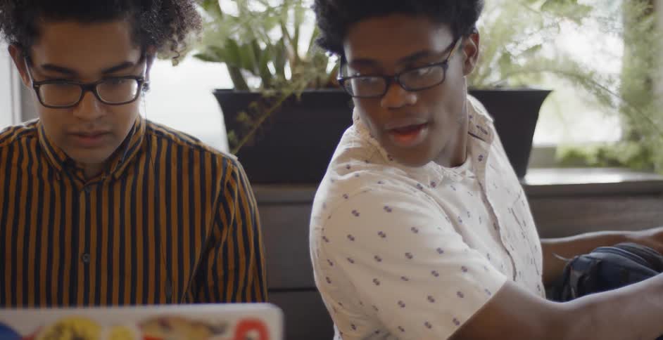 Two black people working on a project together on a laptop