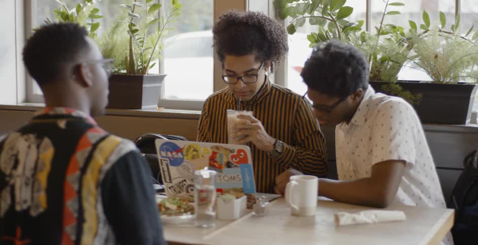 Three people sit around a table talking and having drinks