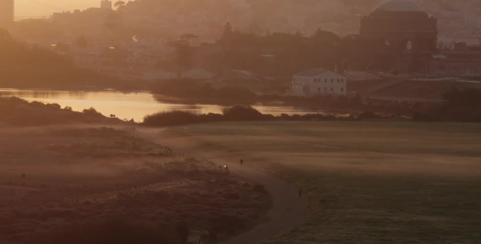 People walking down the road towards a river near a small town
