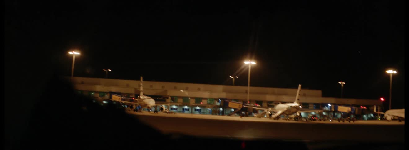 An airport vehicle is traveling across the tarmac at an airport at night