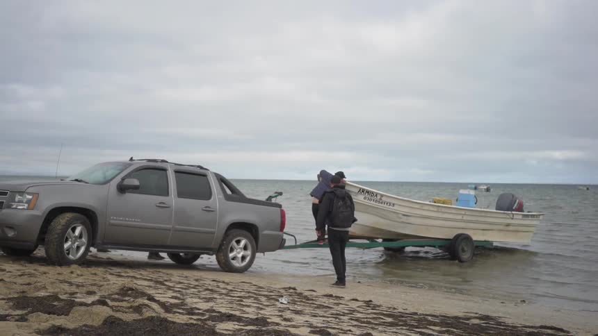 Small boat on a trailer is being pushed into the lake