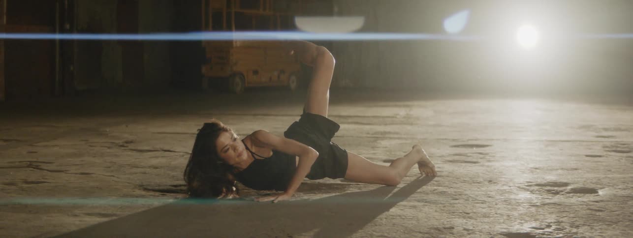 Woman dances solo with bare feet on the concrete floor indoors