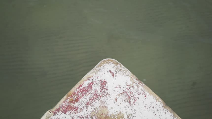 The front of a boat floats over rippling water