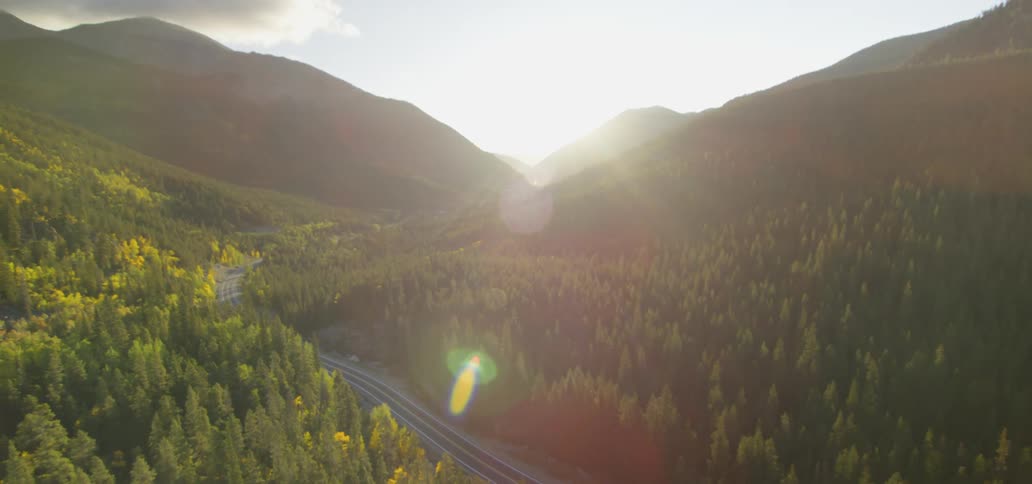 A road runs between forest covered mountains