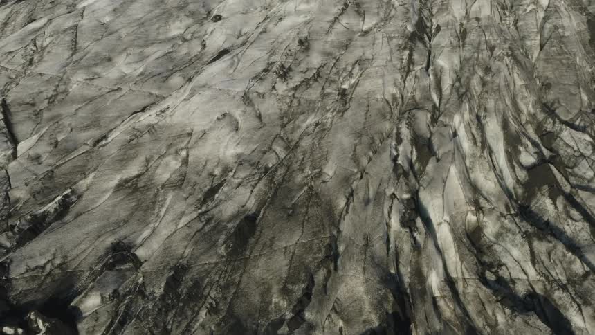 The camera looks down towards a dark glacier