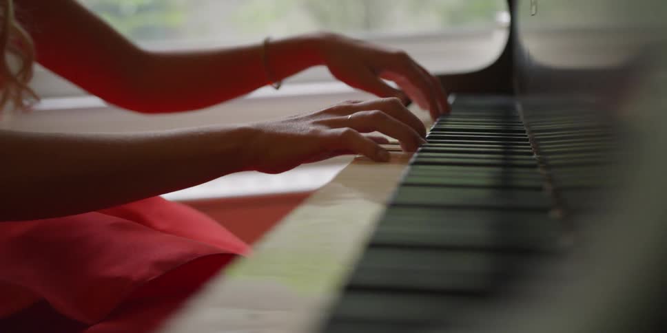 A girl wearing a red dress playing the piano