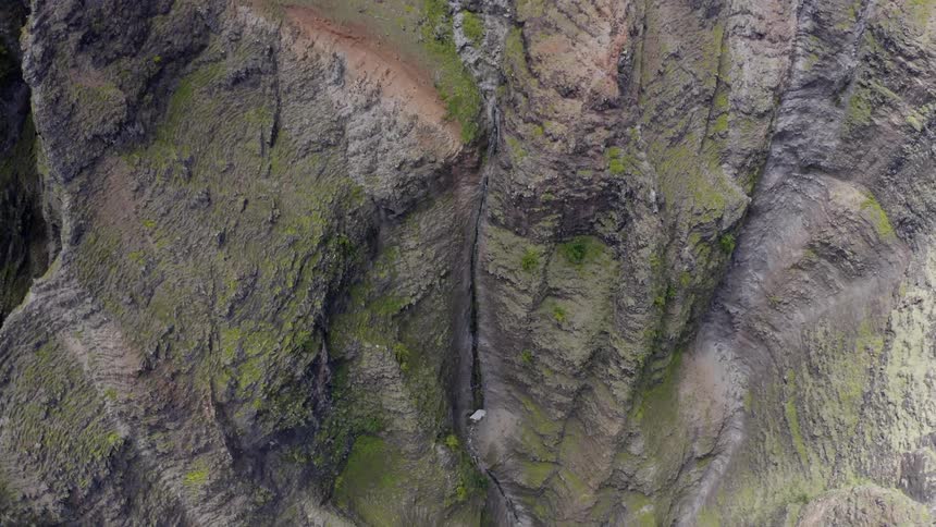 Cliffs covered with grass drop off to a rocky base