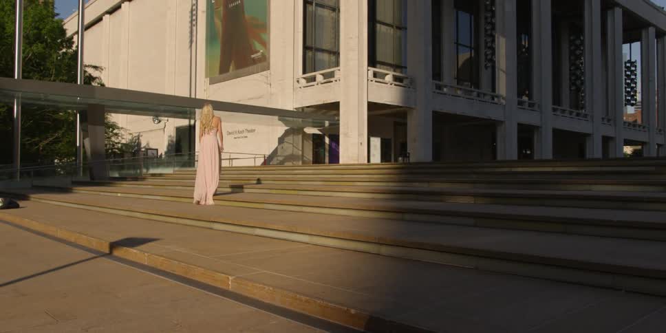 Woman in long dress walks up steps outside during sunset