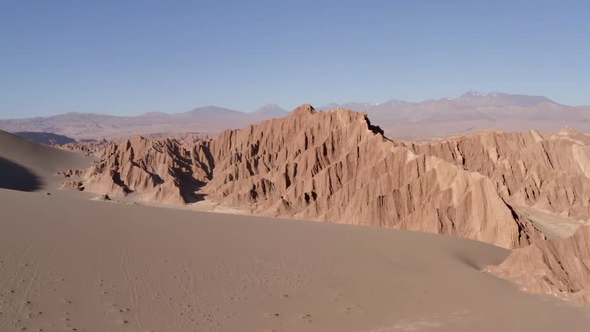Sand and mountains sit under a blue sky
