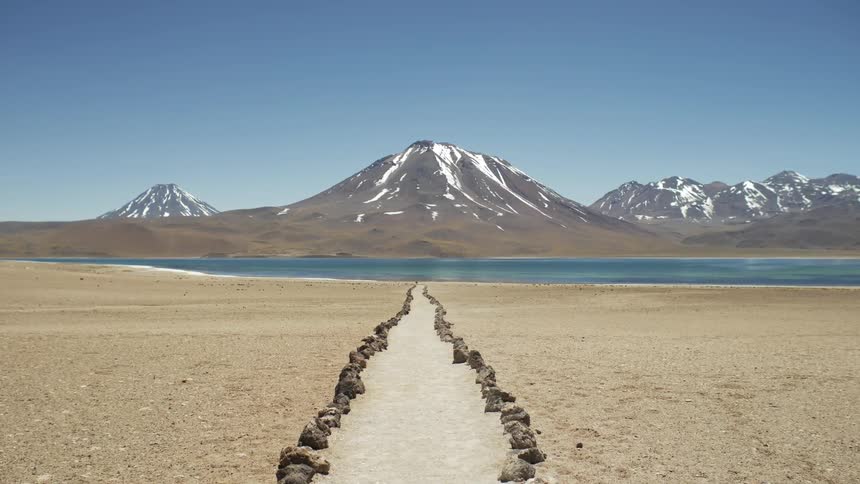 A rock lined road leading to a lake and mountain