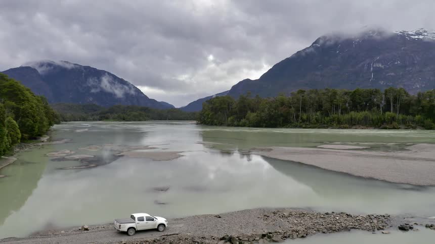 White truck driving on rock path across river bed in the mountains