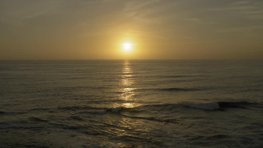A sunset over the ocean as waves ebb and flow