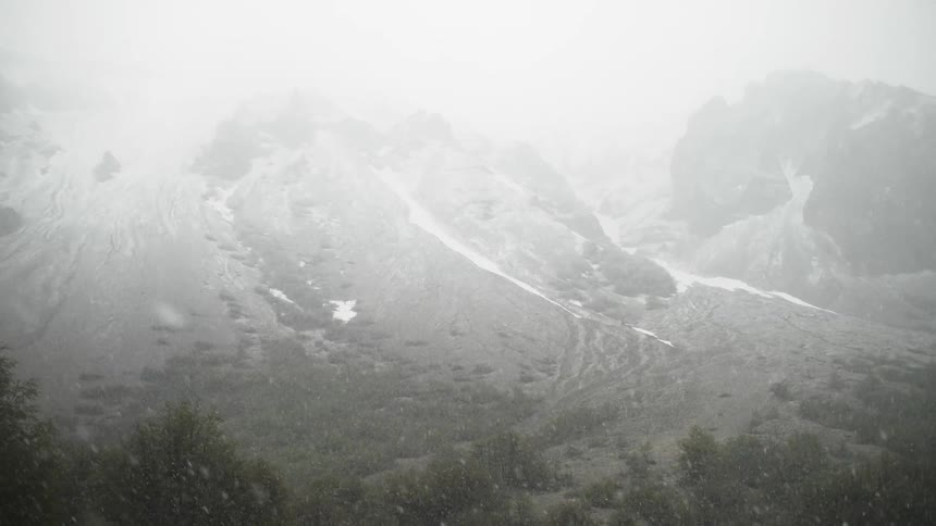Winter snow falls in mountains on a foggy day