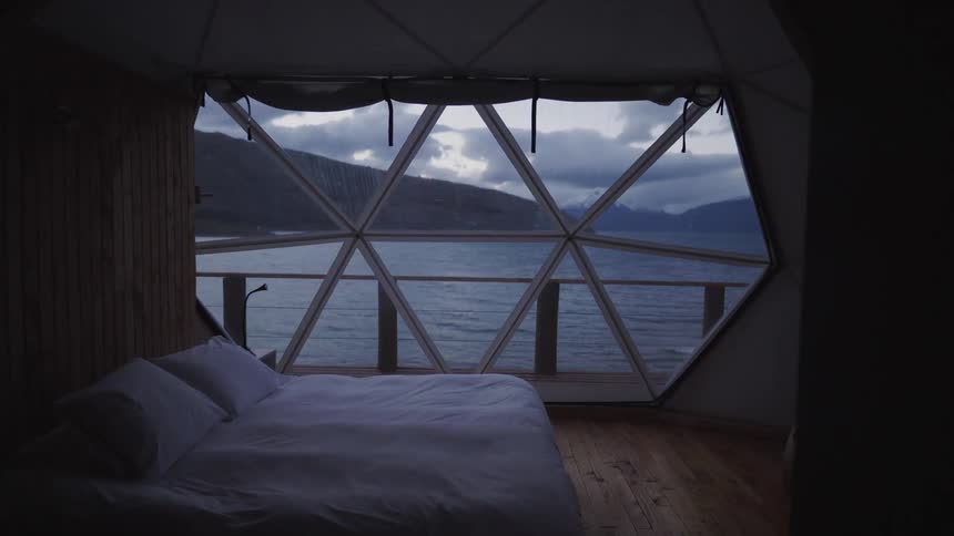 A bedroom with hardwood floors and a tent style opening on the water