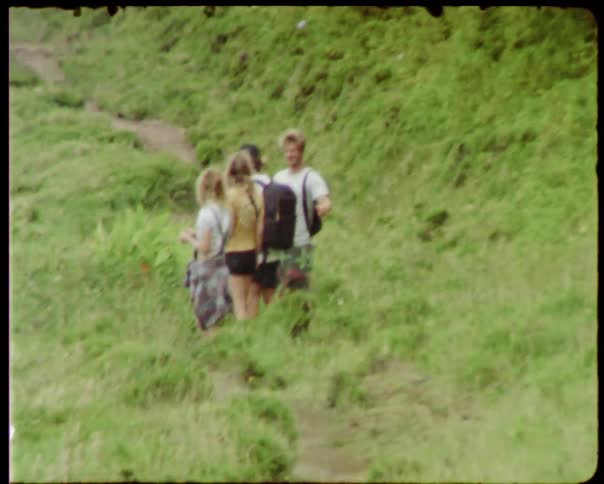 Vintage film of friends hiking on a grassy hill
