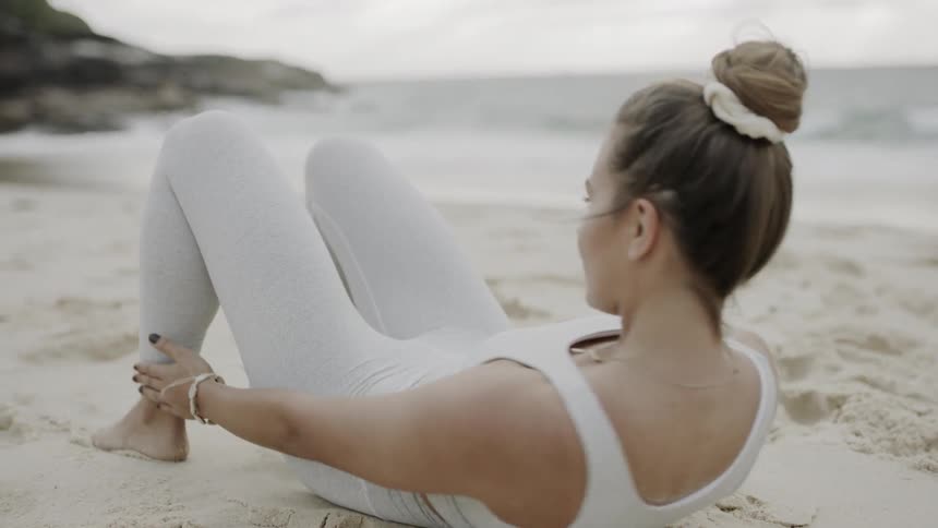 Woman does exercises on the beach
