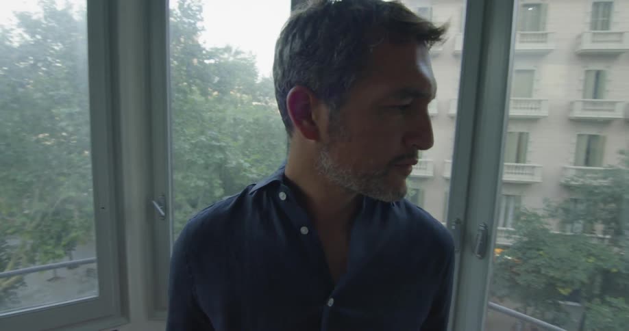 A man inside a glass lined structure looking outside