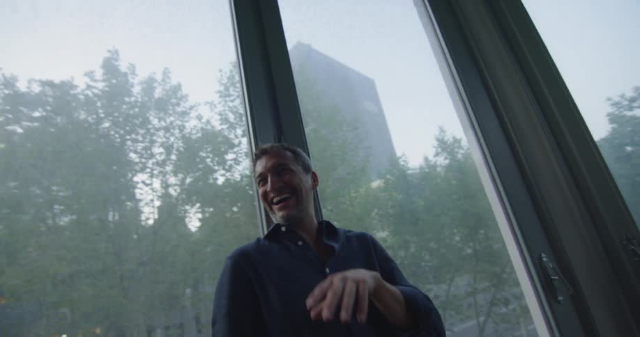 Man laughing in a room surrounded by windows