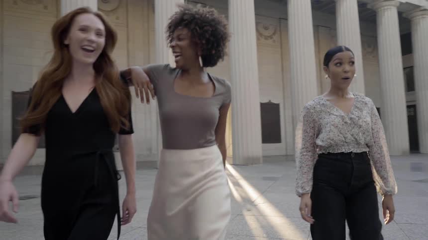 Three women walk through a courtyard as a photographer takes pictures of them