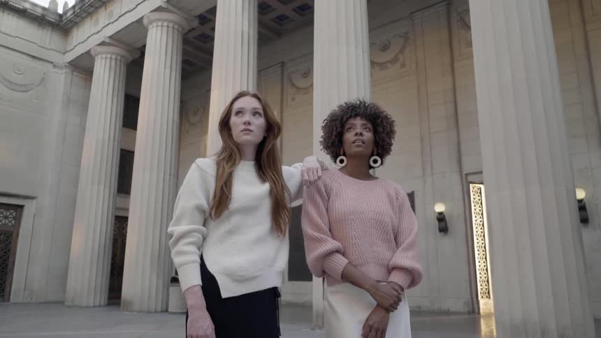 A white woman resting on the shoulder of a black woman at a courthouse