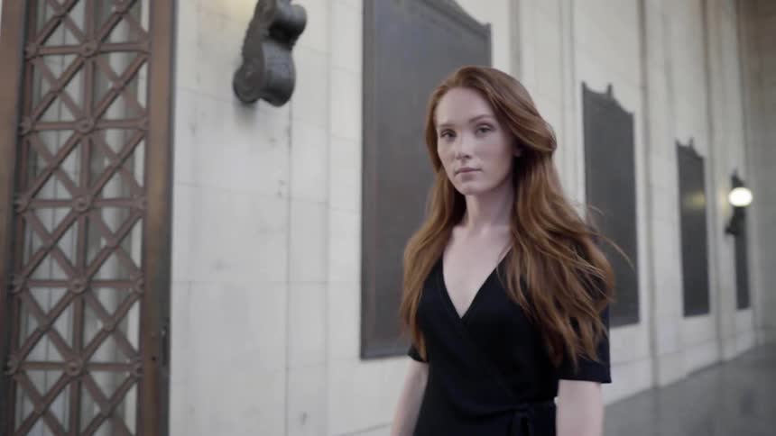 A woman walking towards the camera while smiling flirtatiously