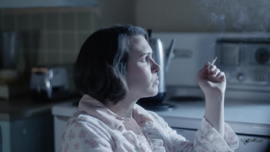 Woman smoking a cig in her kitchen