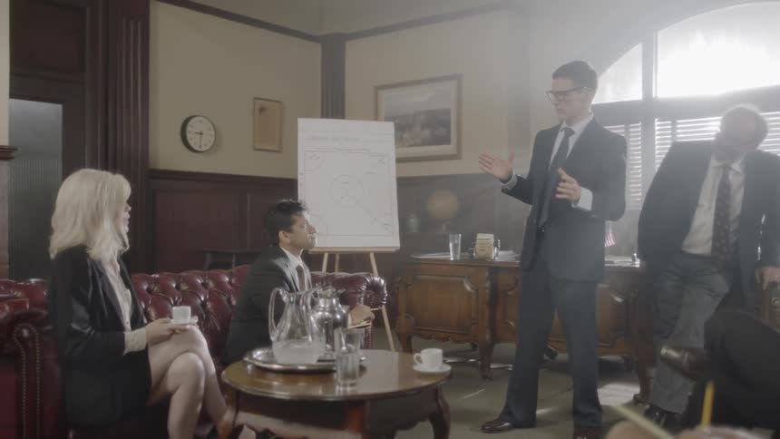 A man is talking to a group of people indoors