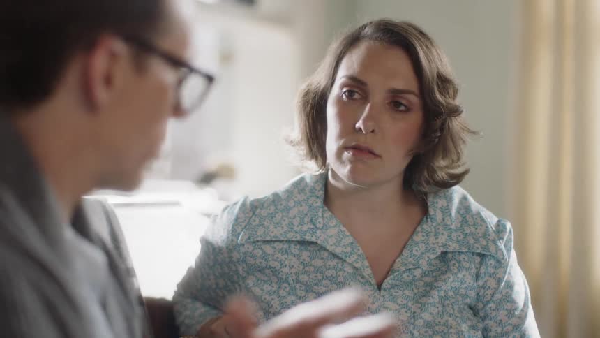 Man in glasses talks to woman sitting to his left