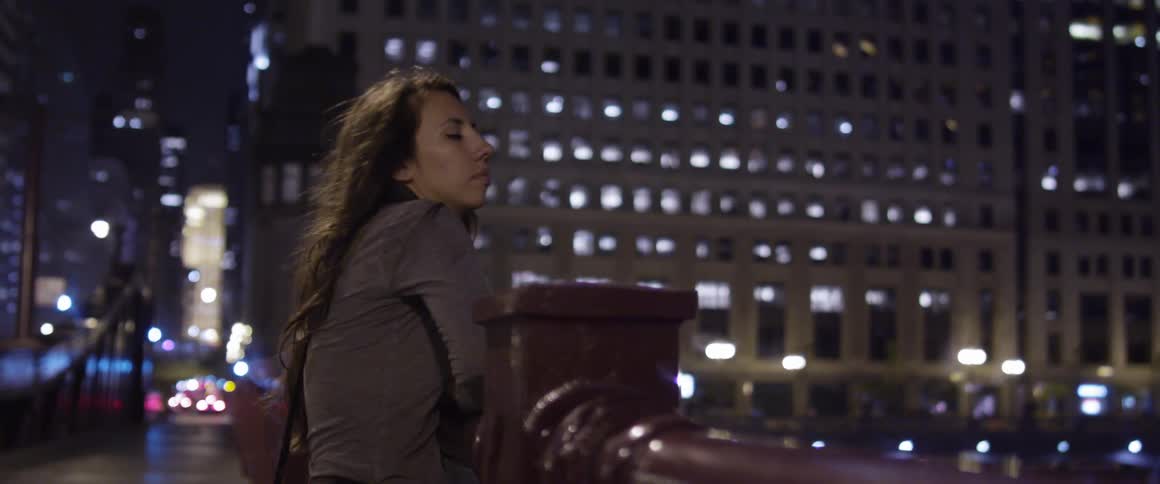 A woman is looking at a city in the night