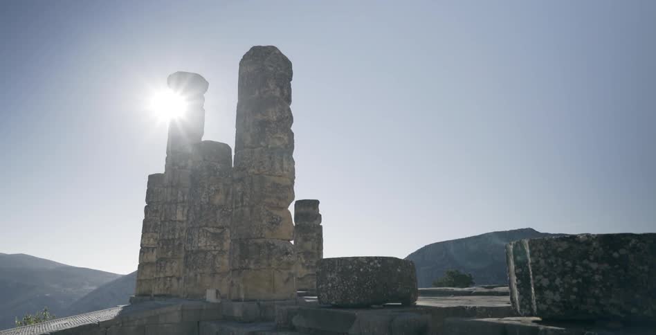 Bright sunlight shines behind a stone monument