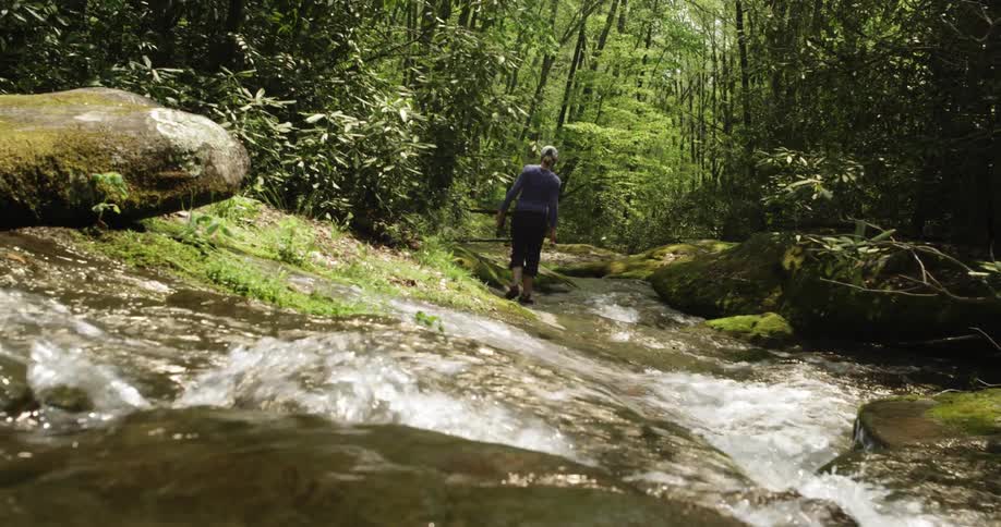A woman is traveling along a stream on a sunny day