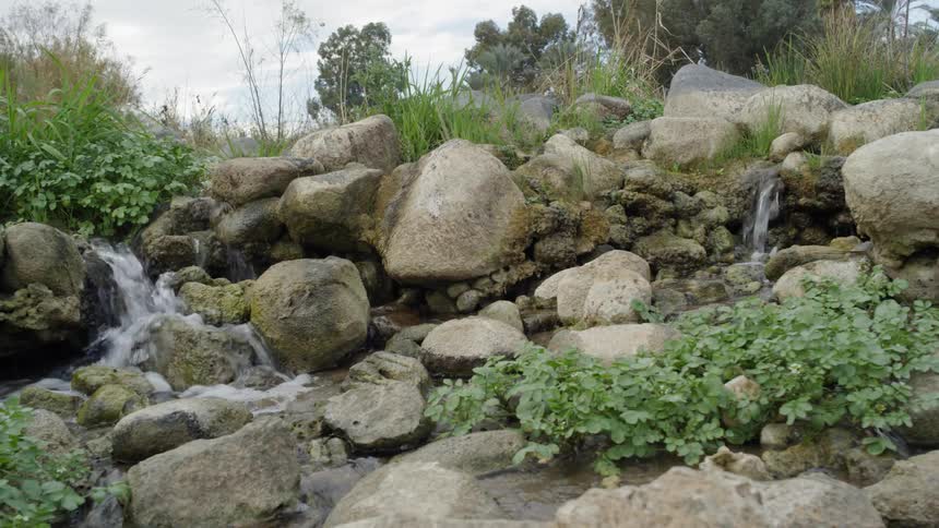 Water from a creek flows swiftly in between a group of large rocks
