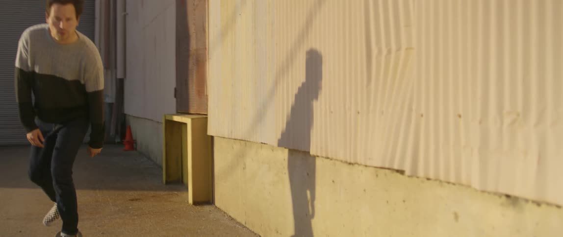 A man skateboards beside a building