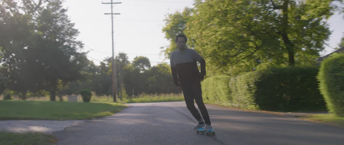 Man rides skateboard along neighborhood street