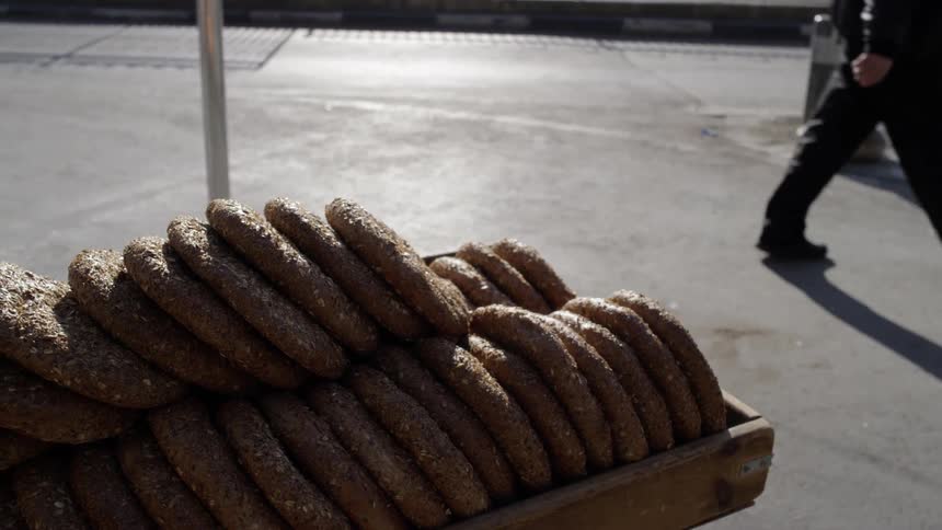 A man walks by a tray of baked goods outside on a sidewalk