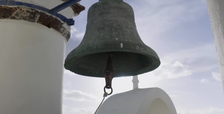 A large bell hangs from a building