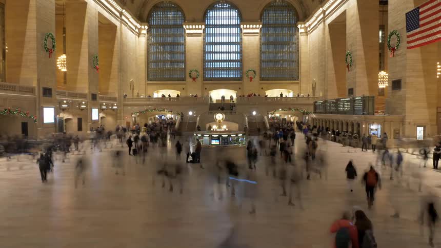 A busy station scene decorated with wreaths and the star spangled banner