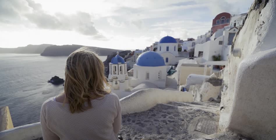 Woman looking at a village of white buildings on a windy day