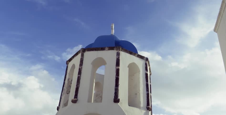A white and blue domed building rests against a blue and cloudy backdrop