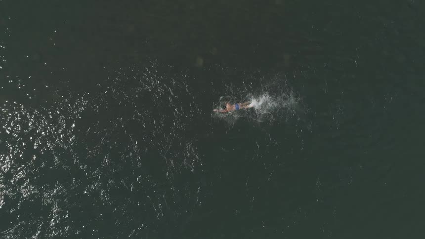 A person swims in the ocean on a sunny day