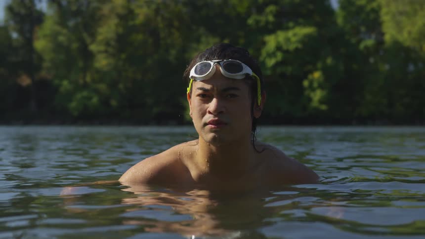 A man sits in a lake and looks around