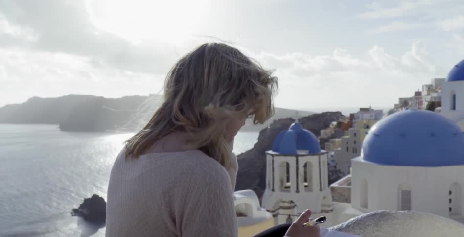A woman writing outside in a coastal town