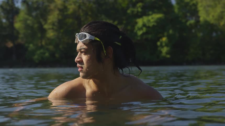 An asian man with swimming goggles in a body of water