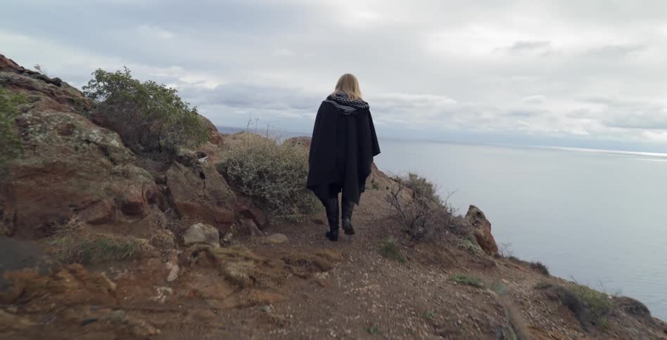Woman walks a rocky path near the ocean