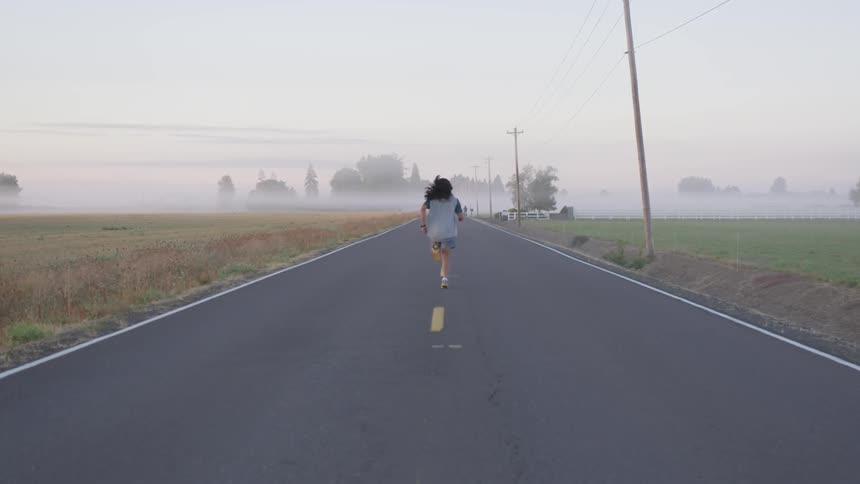 Person runs directly down the middle of the road away from the camera