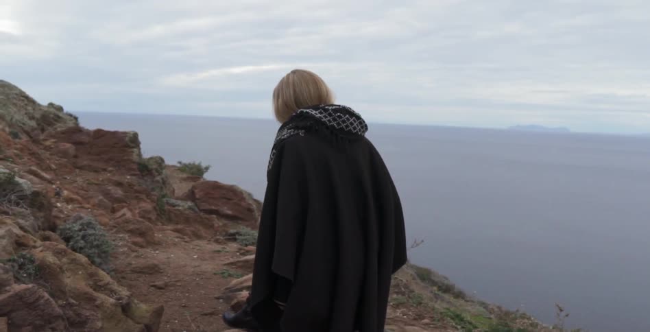 A woman travels along a steep cliff on a cloudy day