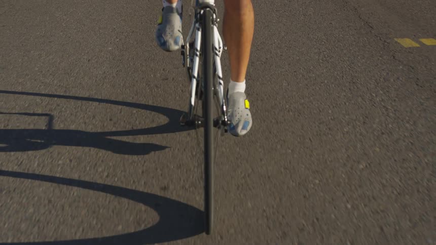 A person pedals a bike down a street