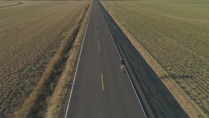 Aerial view of person biking down right side of highway