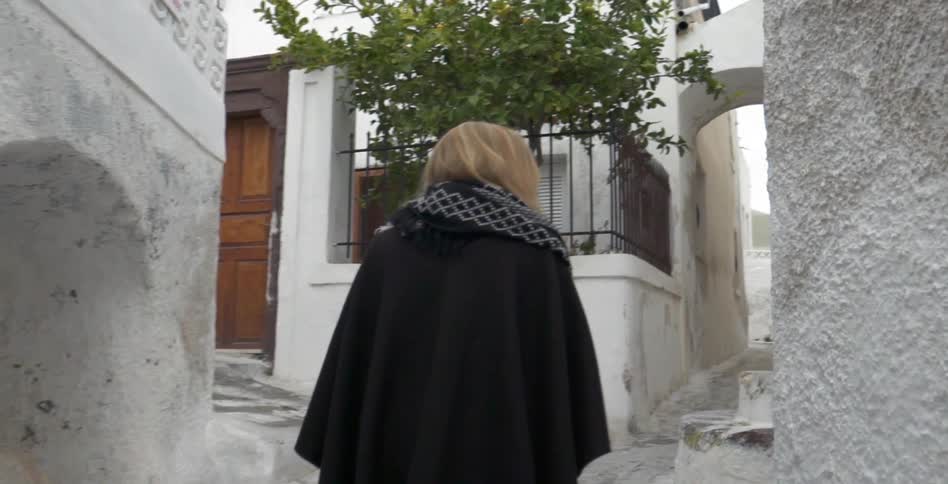 Woman wanders an alley in a sunny village